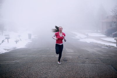 Full length of woman running on snow covered landscape