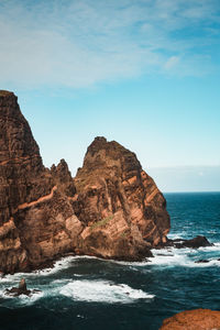 Rock formations by sea against sky