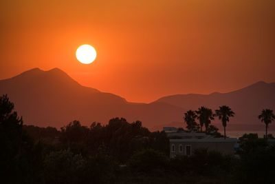 Scenic view of silhouette mountains against orange sky