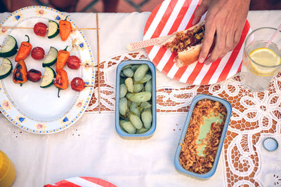 Cropped hand of person holding burger in plate on table at party