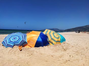 Multi colored umbrellas on beach against clear blue sky