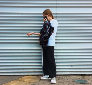 Side view of a young woman standing against wall