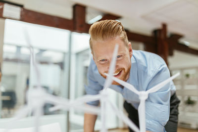 Businessman in office looking at models of wind turbines