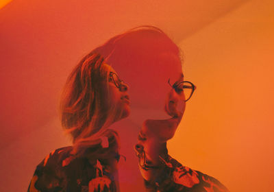 Digital composite image of woman in eyeglasses against orange background
