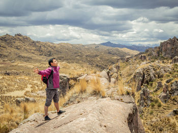 Rear view of man standing on rock against sky