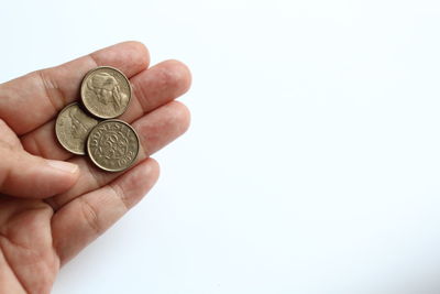 Cropped hand holding coin against white background