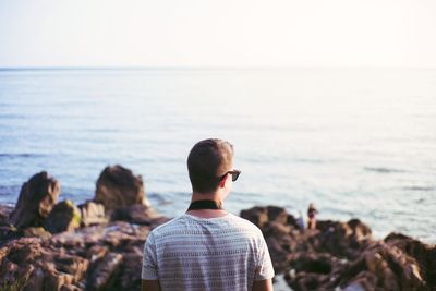 Rear view of man looking at sea against sky