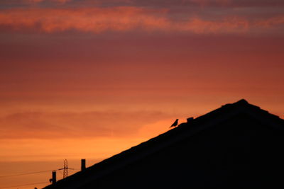 Low angle view of silhouette building against sunset sky