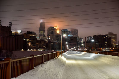 Illuminated snow covered bridge in modern city at night