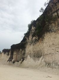 Rock formation on beach against sky