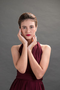 Portrait of young woman against gray background