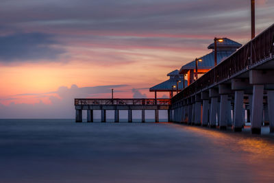 Pier over sea against sky during sunset