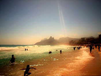 People on beach against sky during sunset