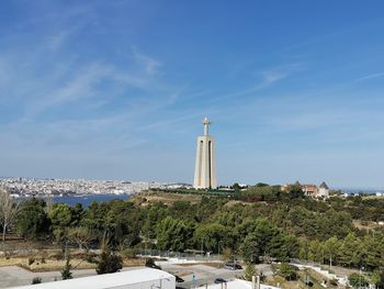 View of lighthouse by buildings against sky