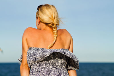 Rear view of woman standing by sea against sky