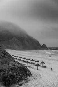 Scenic view of foggy beach against moody sky