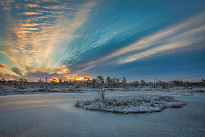 Scenic view of snow covered landscape against sky at sunset