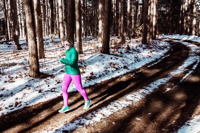 Full length rear view of woman in snow covered forest