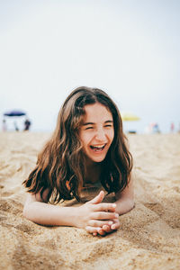 Little girl lying on the sand having fun and laughing