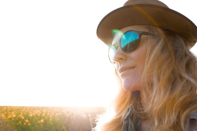 Woman in hat and sunglasses against clear sky