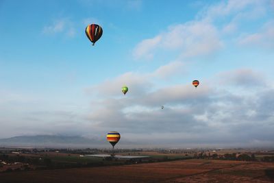 Hot air balloons flying over landscape against sky