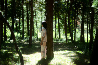 Man standing by trees in forest