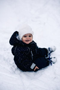 Portrait of smiling baby girl sitting on snow covered land