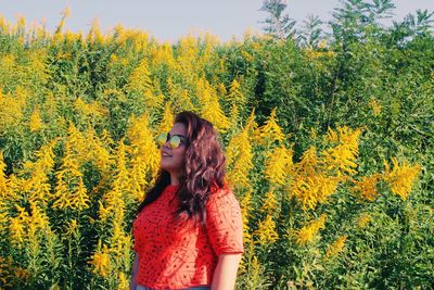 Portrait of young woman standing by plants