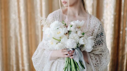 Midsection of woman holding white flowers