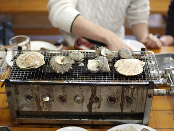 Midsection of man by seashells on barbecue grill