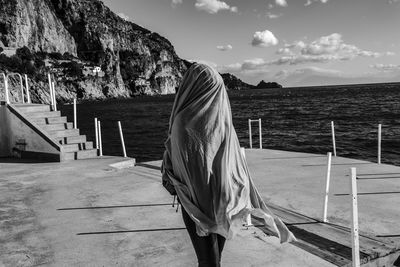 Rear view of woman on sea shore against sky