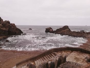 Rock formations on shore against sky