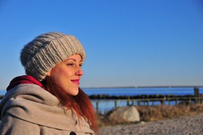 Close-up of young woman on beach against clear blue sky