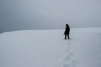 Woman standing on snowcapped mountain against sky