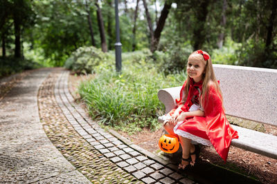Portrait of smiling girl wearing costume sitting on bench at park