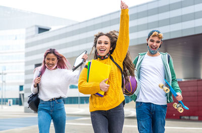 Cheerful friends carrying book outdoors