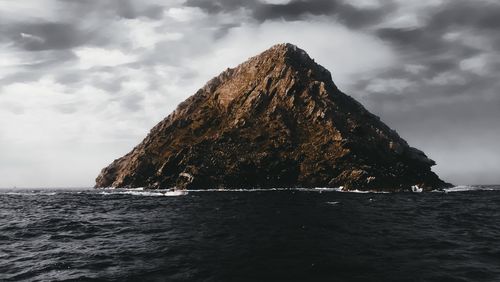 Rock formation in sea against sky