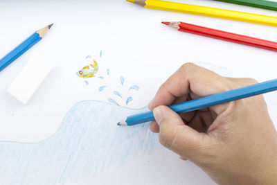 High angle view of hand holding pencils on table