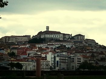 Buildings in city against cloudy sky