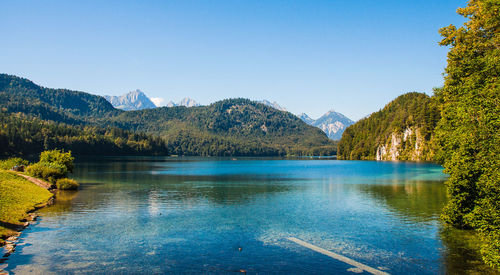 Scenic view of lake and mountains against clear blue sky