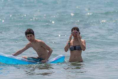 Teenage boy with young sister in sea