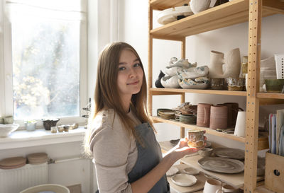 Young beautiful female potter at the ceramic studio. professional artisan with handmade clay cup.