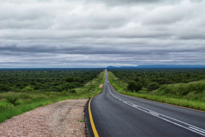 Road amidst field against sky