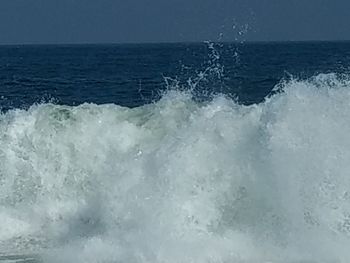 Close-up of wave splashing on sea against sky