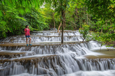 Man standing by waterfall in forest