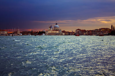 View of buildings at waterfront against cloudy sky