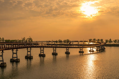 Bridge over river against sky during sunset