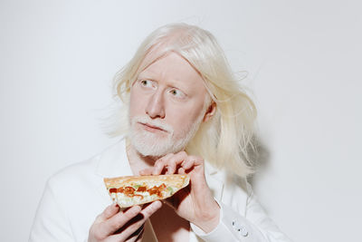 Portrait of young woman eating food against white background