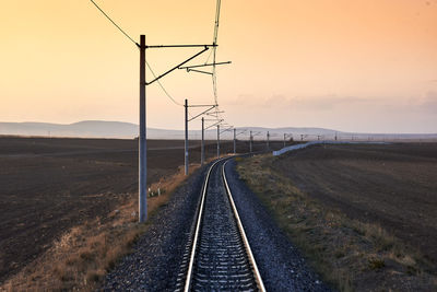 Railroad track against clear sky during sunset