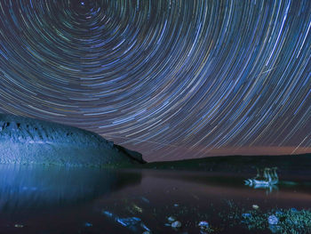 Scenic view of lake against illuminated star trails